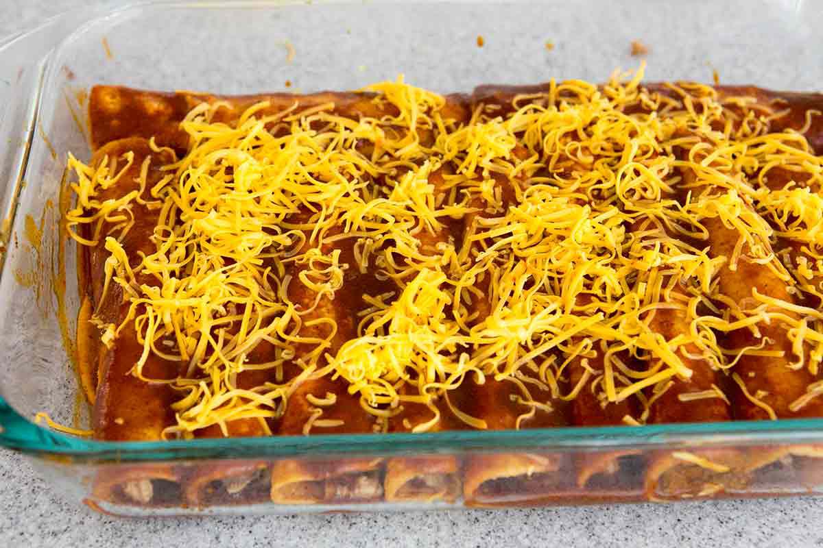 sprinkle homemade chicken enchiladas with grated cheese
