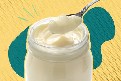 spoonful of mayonnaise lifted from a jar overa a colorful background