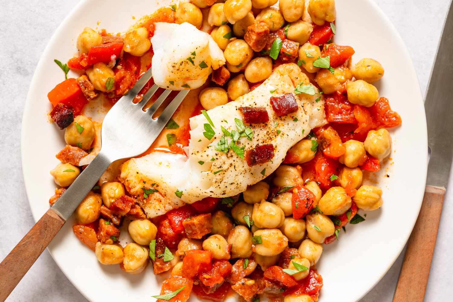 Plate of cod served with chickpeas and garnished with herbs