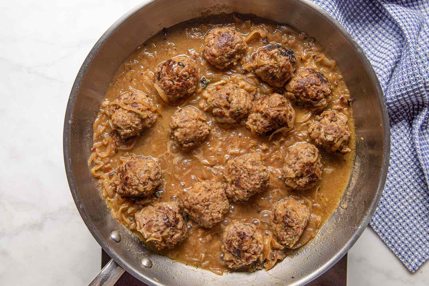 Caramelized Onions, Chicken Broth, and Worcestershire Sauce Mixed With Meatballs in Pan