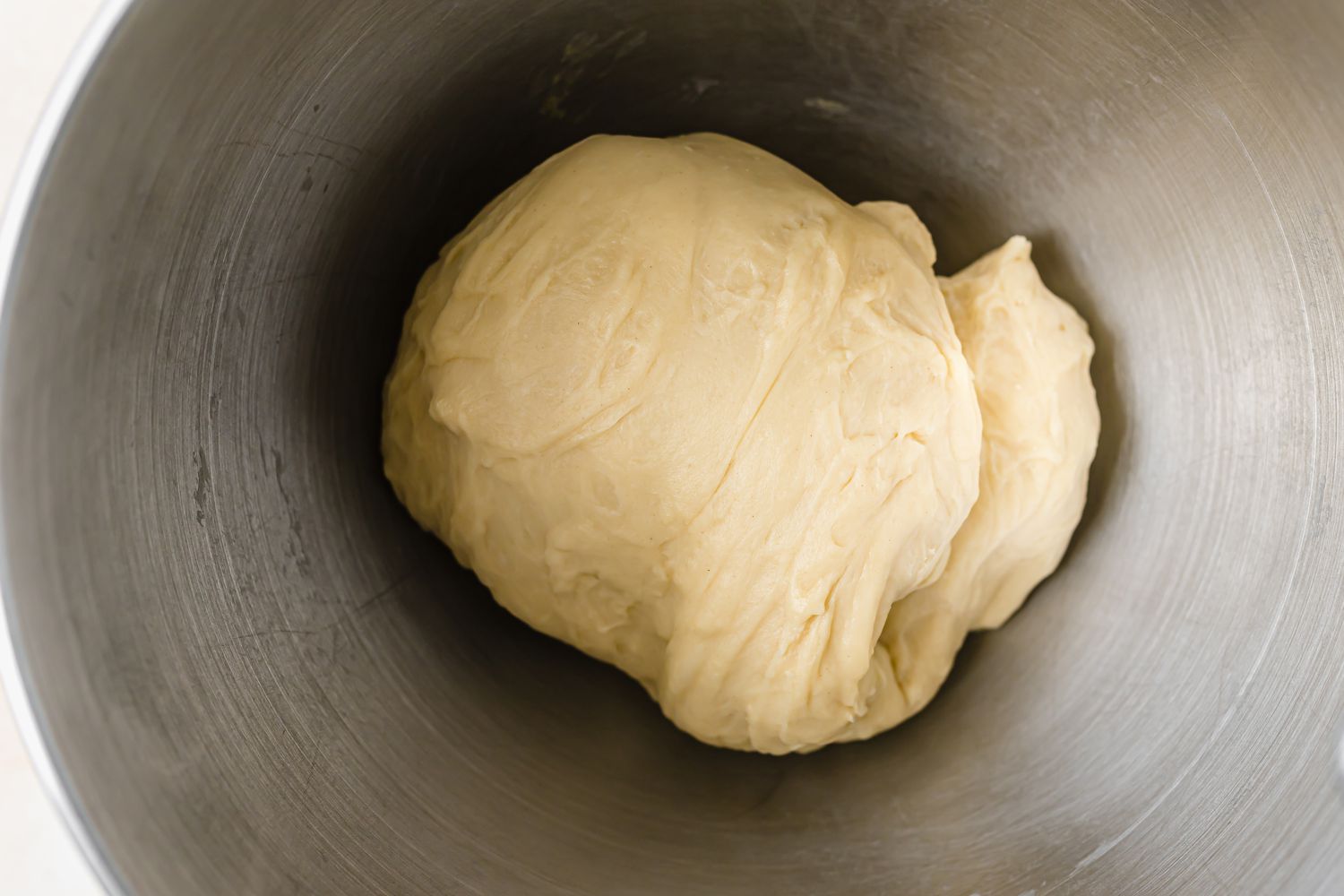 Kneaded dough for pull apart rolls with garlic and parmesan in a mixing bowl.