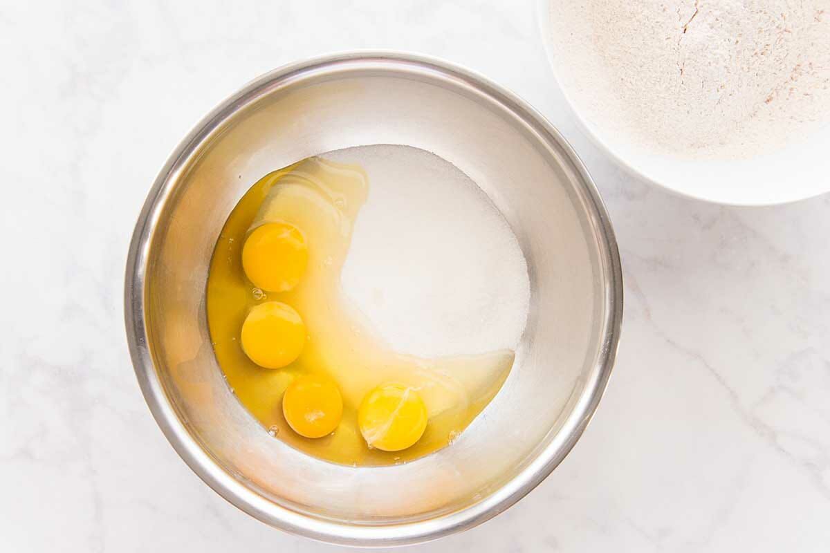 Eggs and sugar added to a metal bowl to make a Pumpkin Snack Cake.
