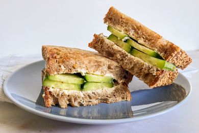 Halved 2-ingredient cucumber sandwich on a plate, with one sandwhich half leaned on another 