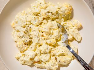 A plate of egg salad with a spoon resting on the side