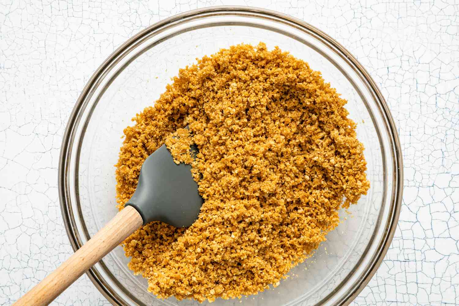 Graham Cracker Pie Crust Mixed Together in a Bowl Using a Spatula for British Banoffee Pie Recipe