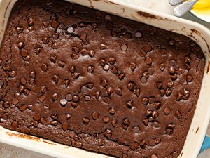 Overhead view of a baking dish of baked batter for Chocolate Dump Cake recipe on a tan countertop