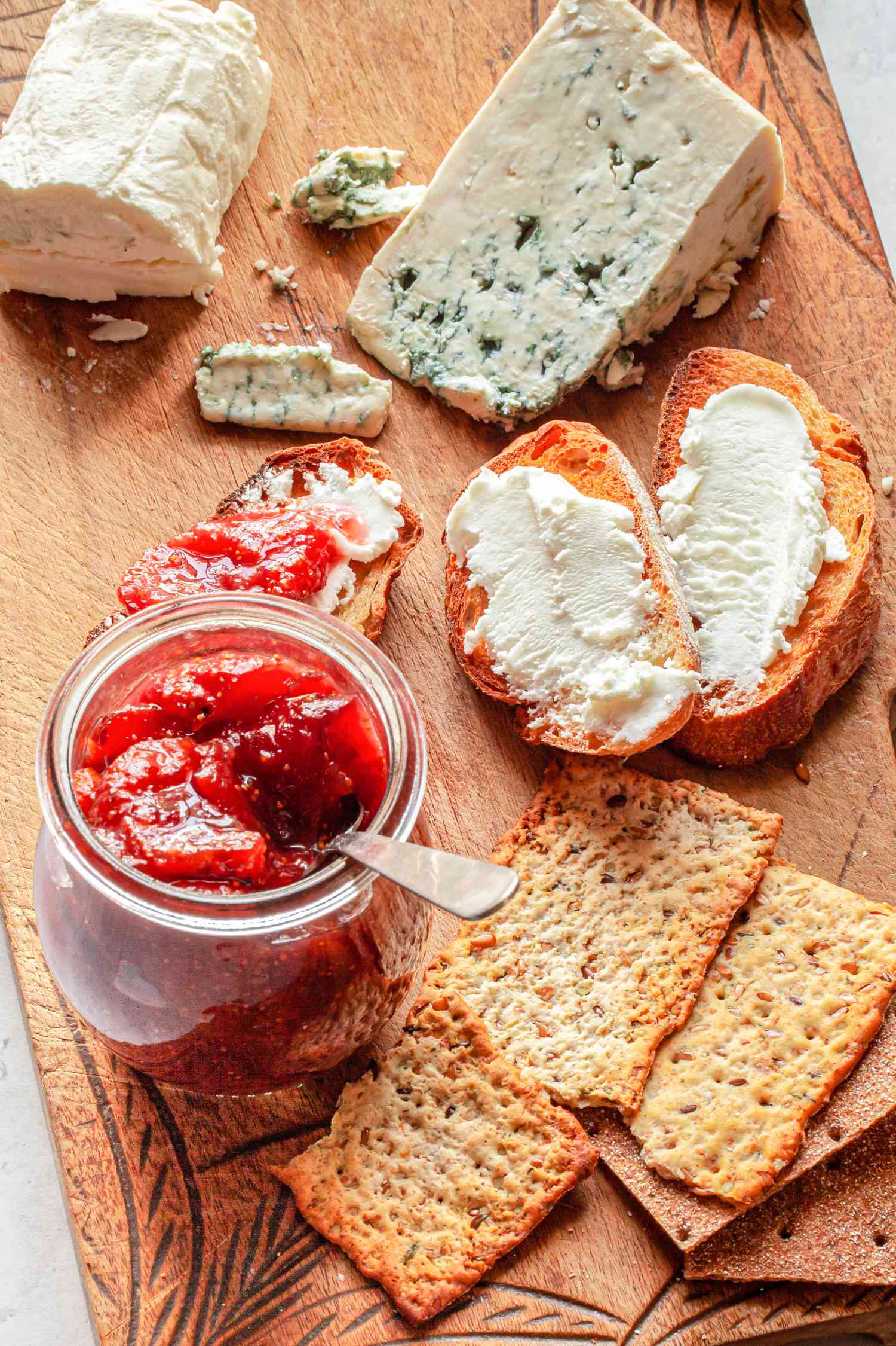 Jar of Fig Preserves on a Charcuterie Board with Crackers, Bread, and Cheese