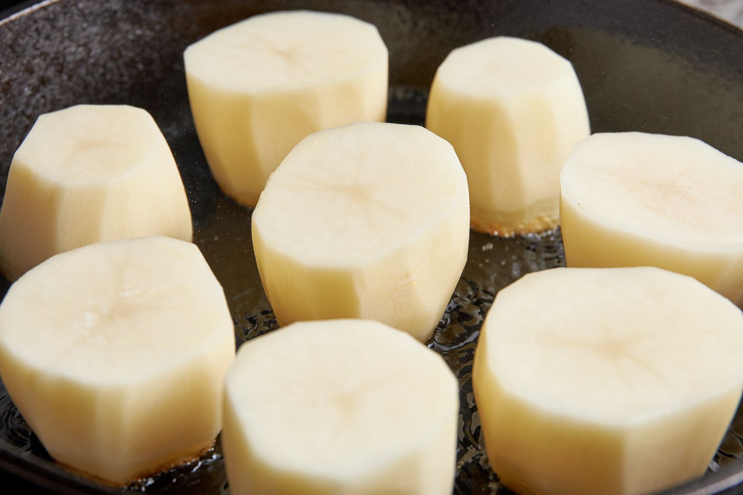 Russet potatoes searing on skillet for fondant potatoes recipe