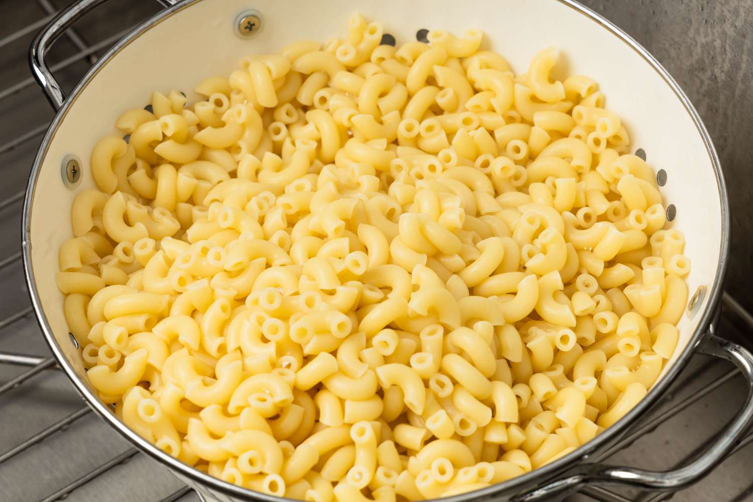 Cooked elbow pasta draining in a colander in the stove for Johnny Marzetti casserole recipe