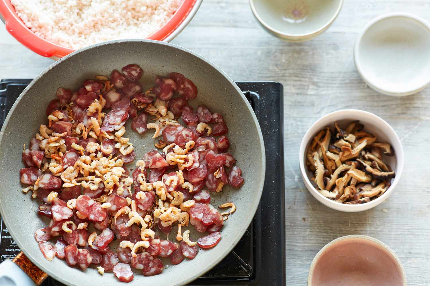 Dried pork added to skillet to make steamed rice with sausage, dried shrimp, and mushrooms