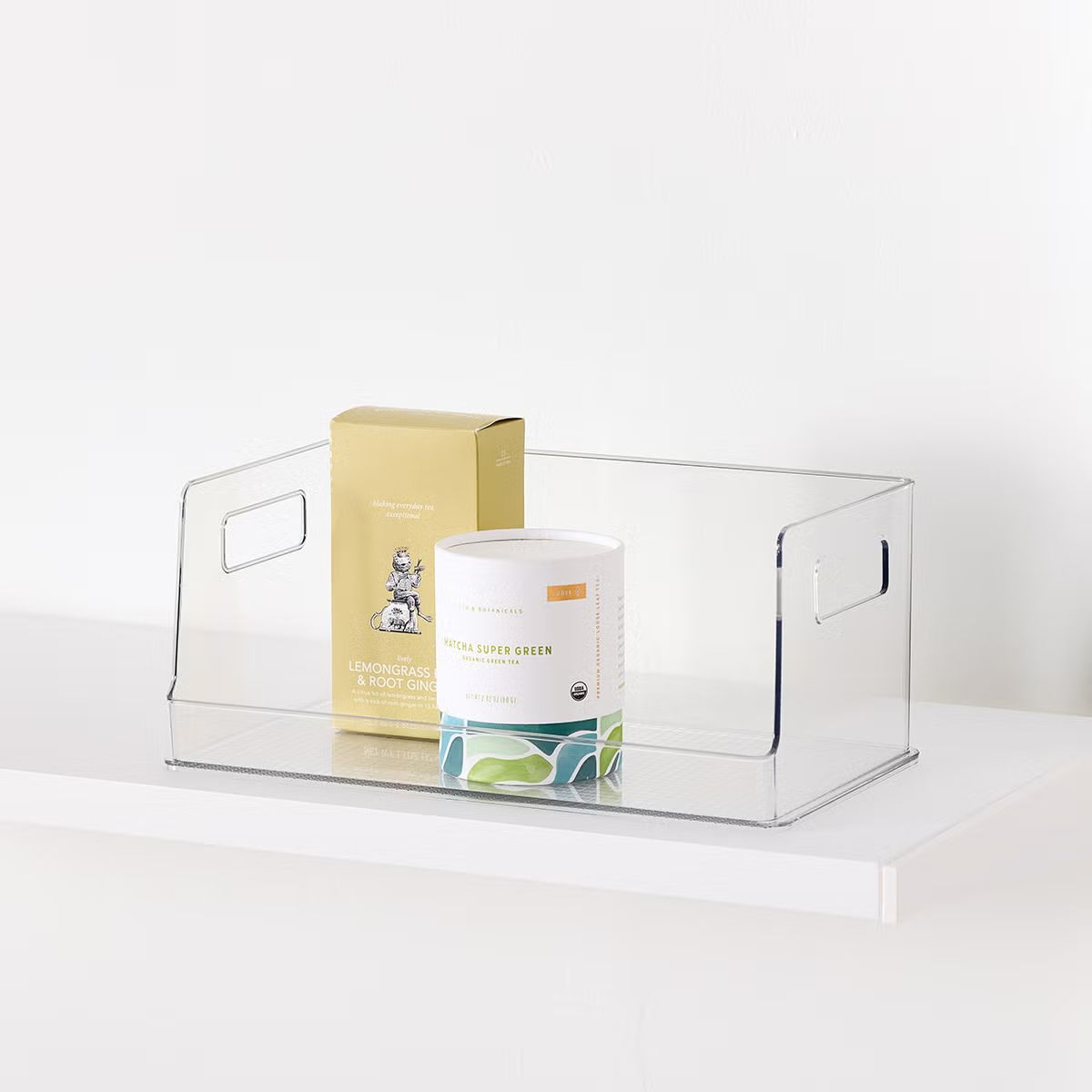 A clear plastic storage bin containing two packaged items on a white surface