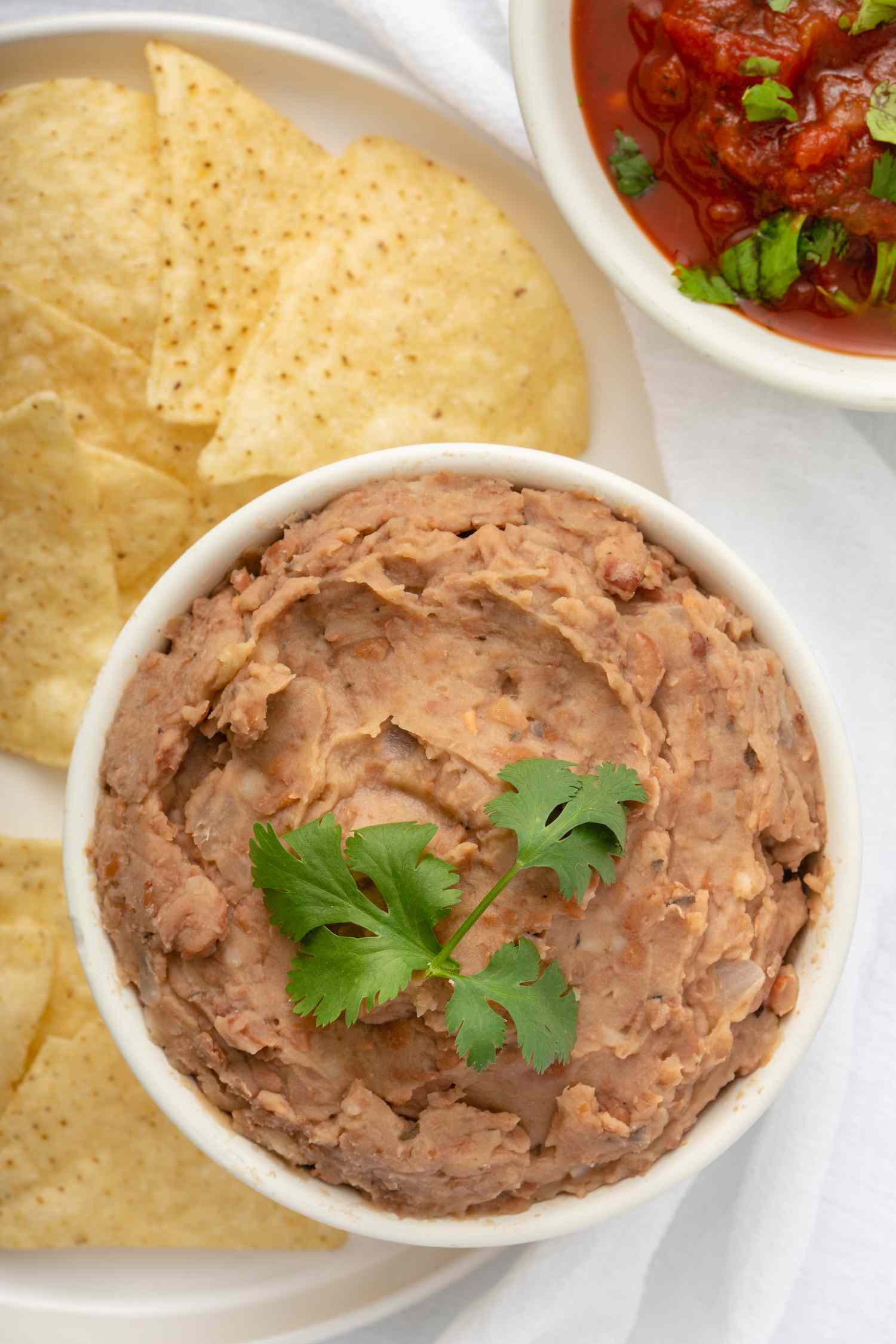 Overhead view of mexican beans served with tortilla chips and salsa.