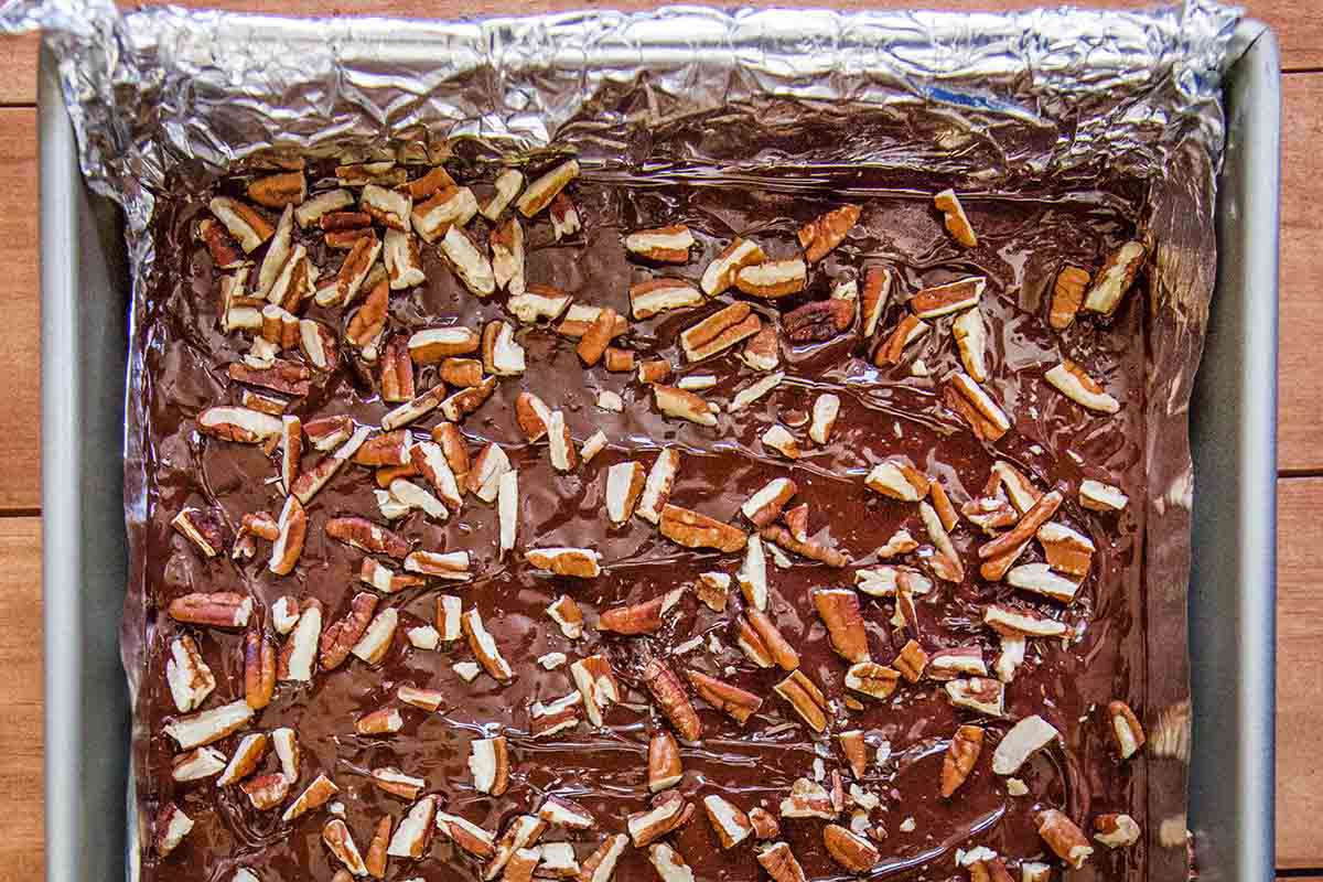 Toffee sprinkled with pecans in a foil lined baking sheet.