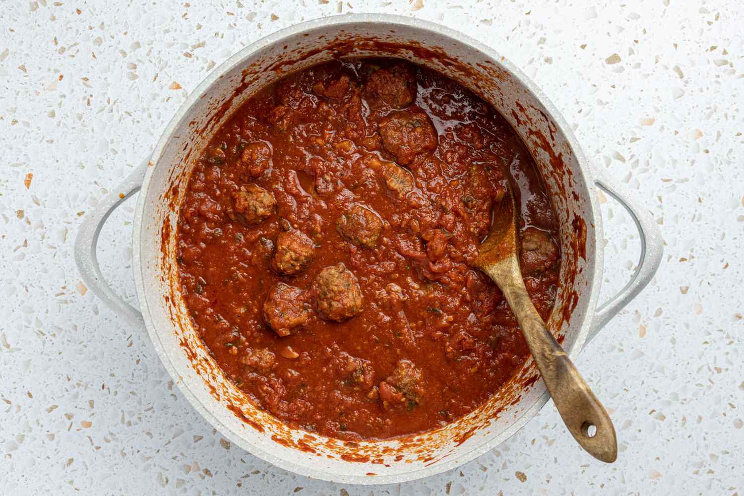 Meatballs Stirred into Pot of Sauce With a Wooden Spoon