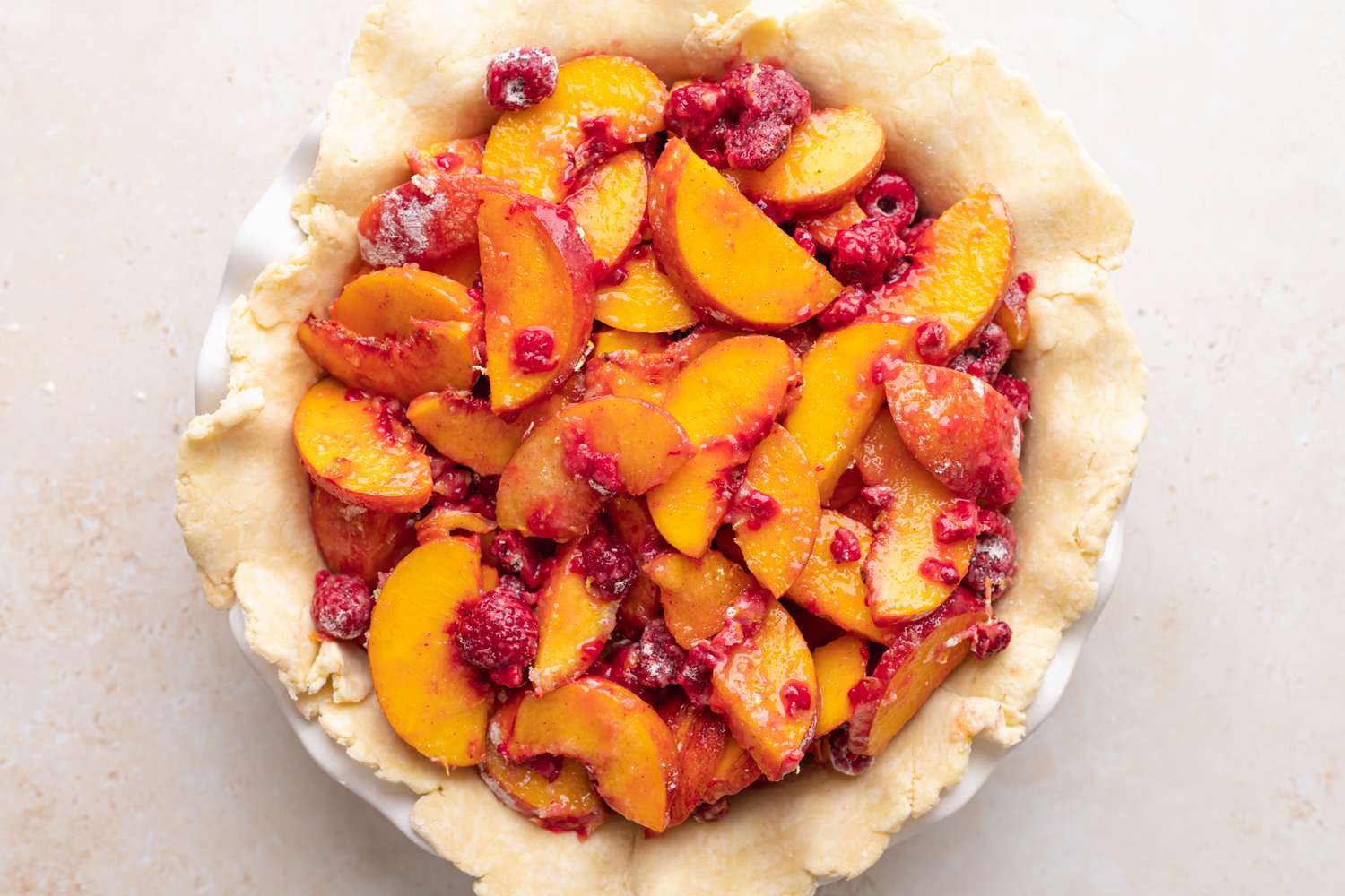 A pie crust filled stone fruit and berry filling to make a pie