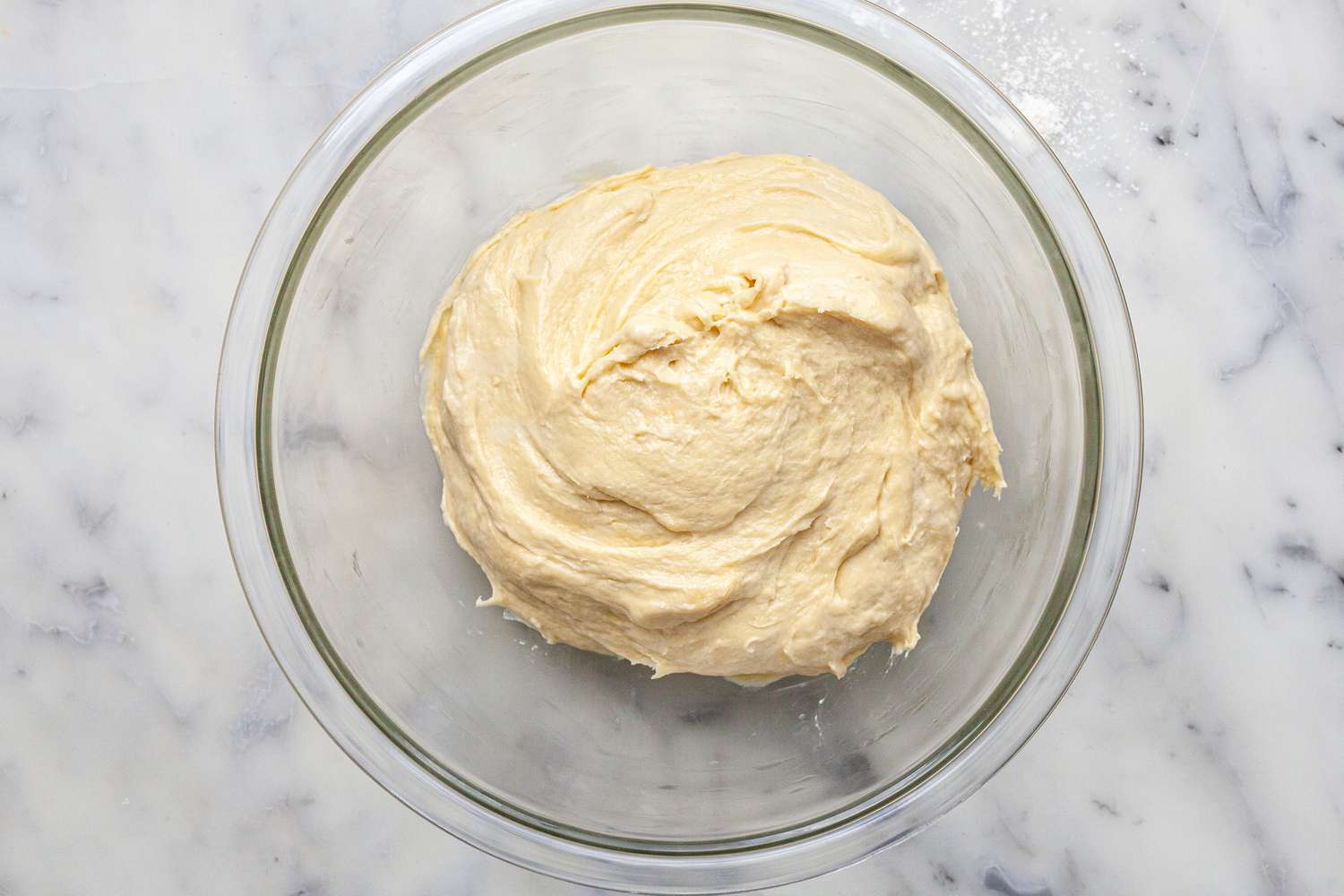 Dough rising in a glass bowl to make homemade brioche buns.