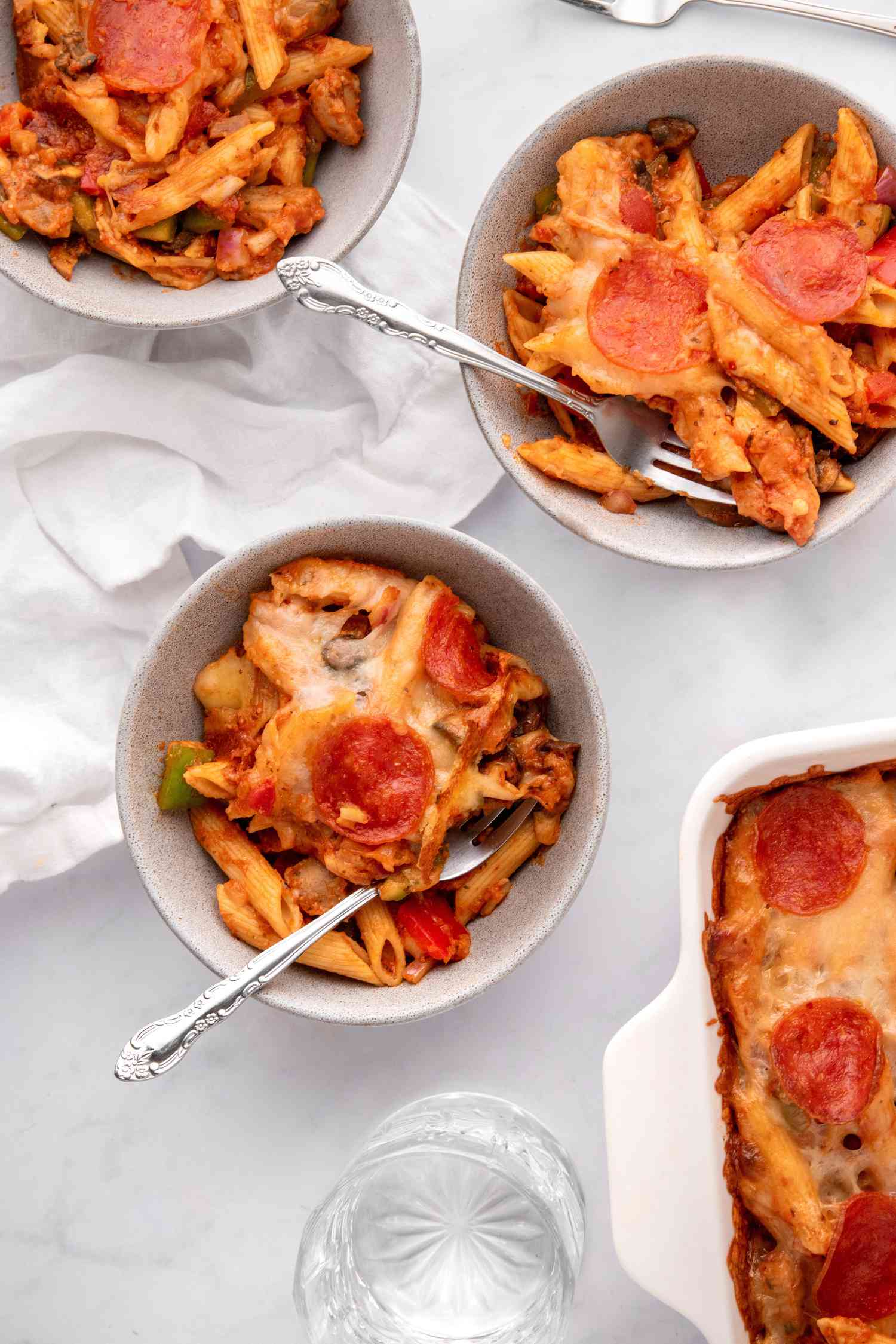 Penne and pepperoni casserole in three small bowls.