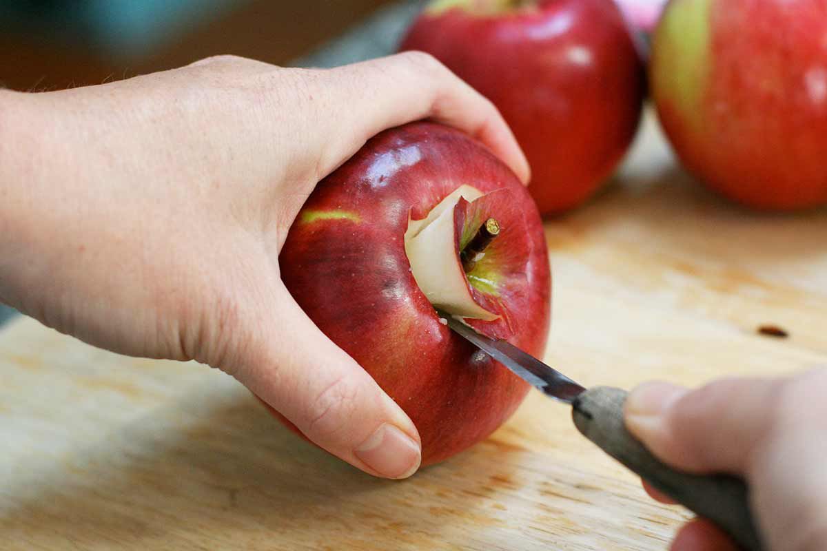 Holes being cut out of the top of apples for stuffing