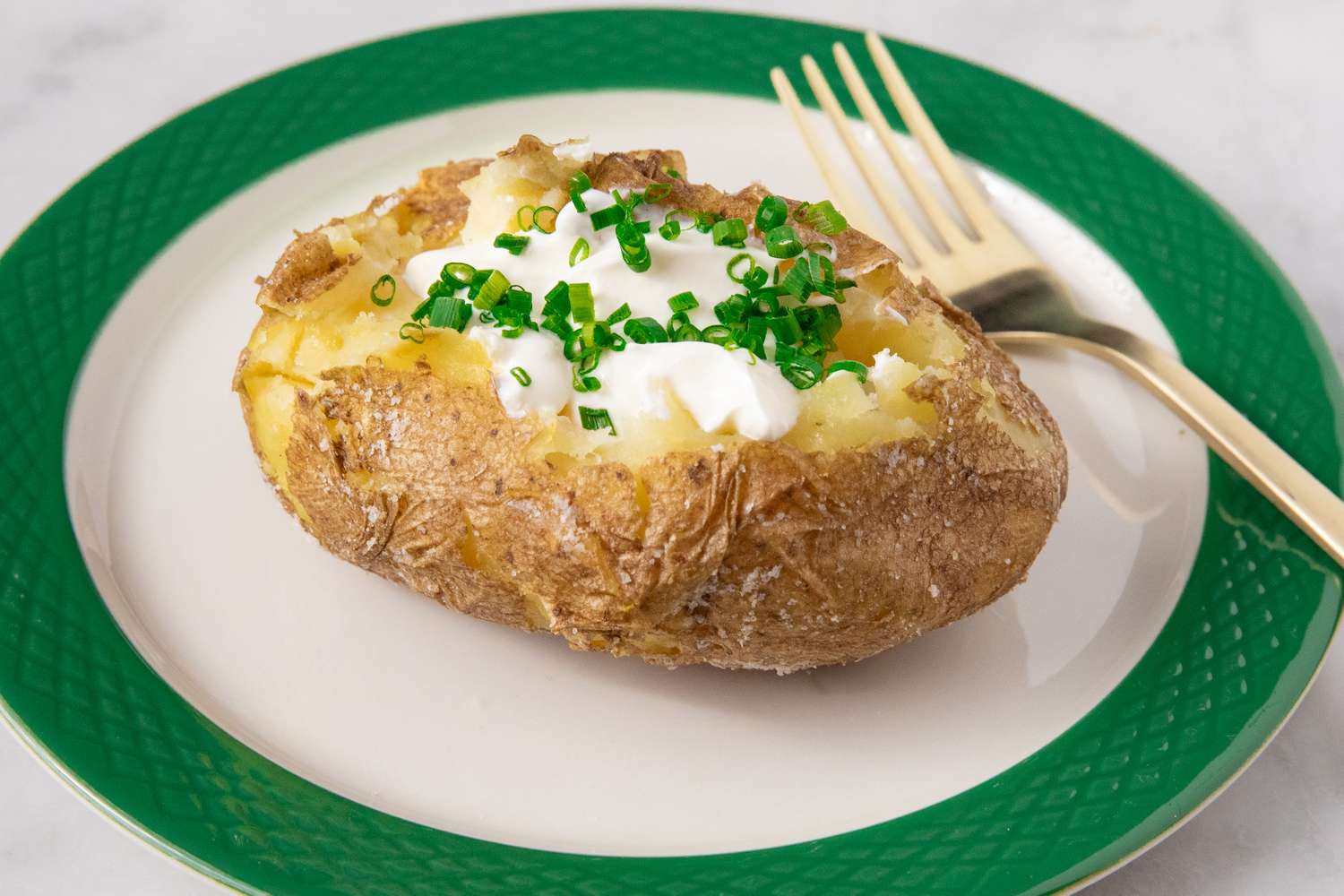 one of Alton Brown's Perfect Baked Potatoes on a plate with a fork