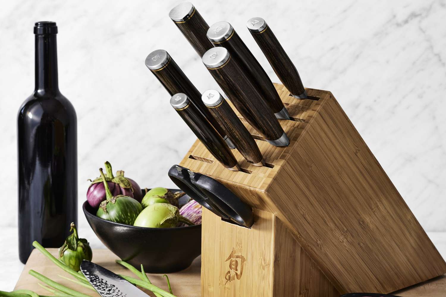 Williams Sonoma Knife Block Next to a Bowl of Eggplants, a Cutting Board, and an Empty Bottle of Wine