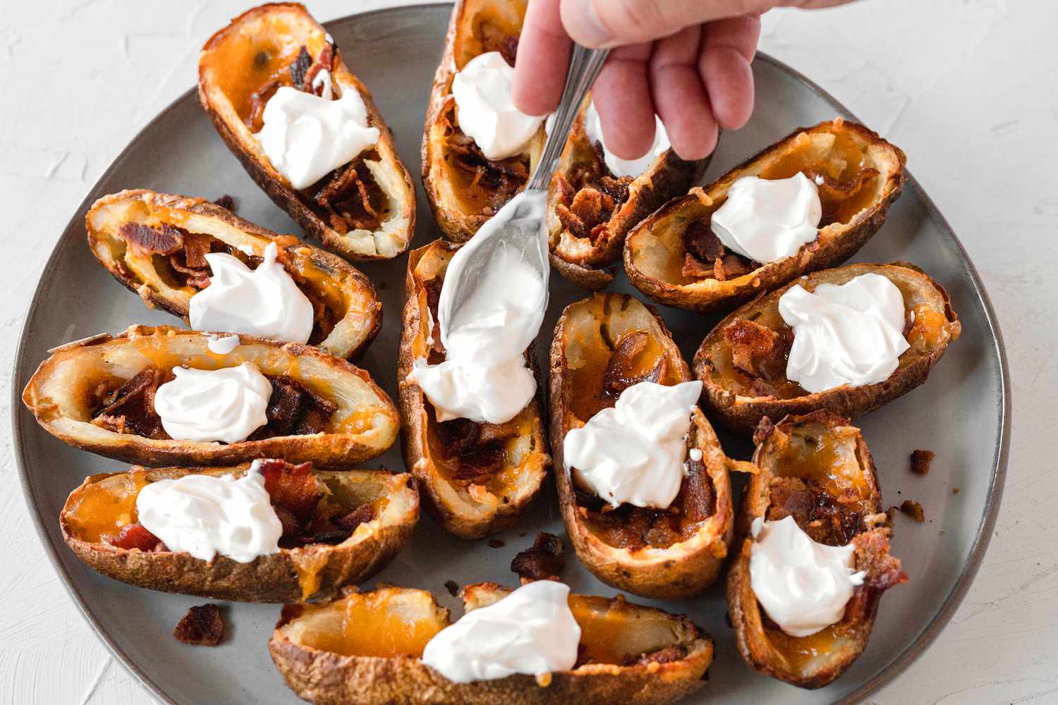 Scooping sour cream on to cooked potato skins