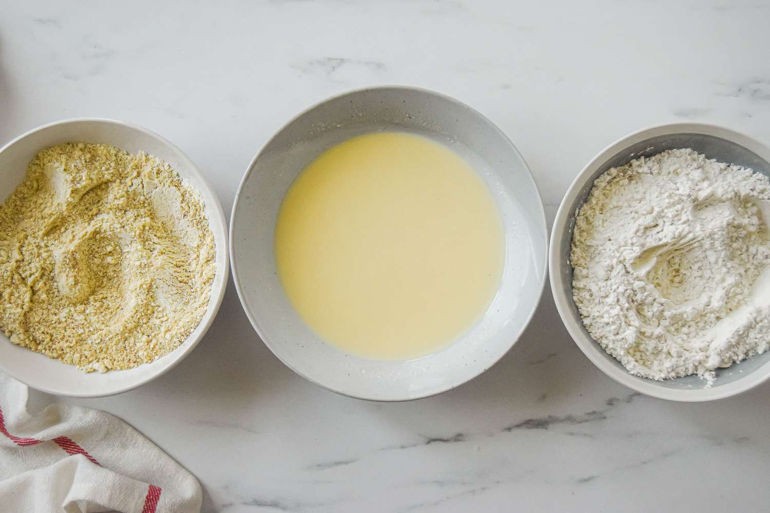 Three bowls with ingredients combined to make a fried green tomatoes recipe.
