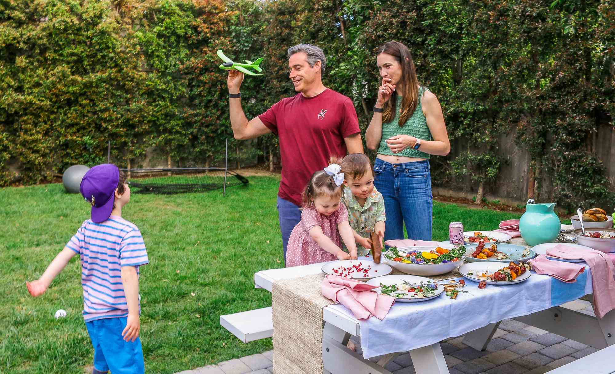 The Pfeffer parents and their three children play outside alongside a table of food