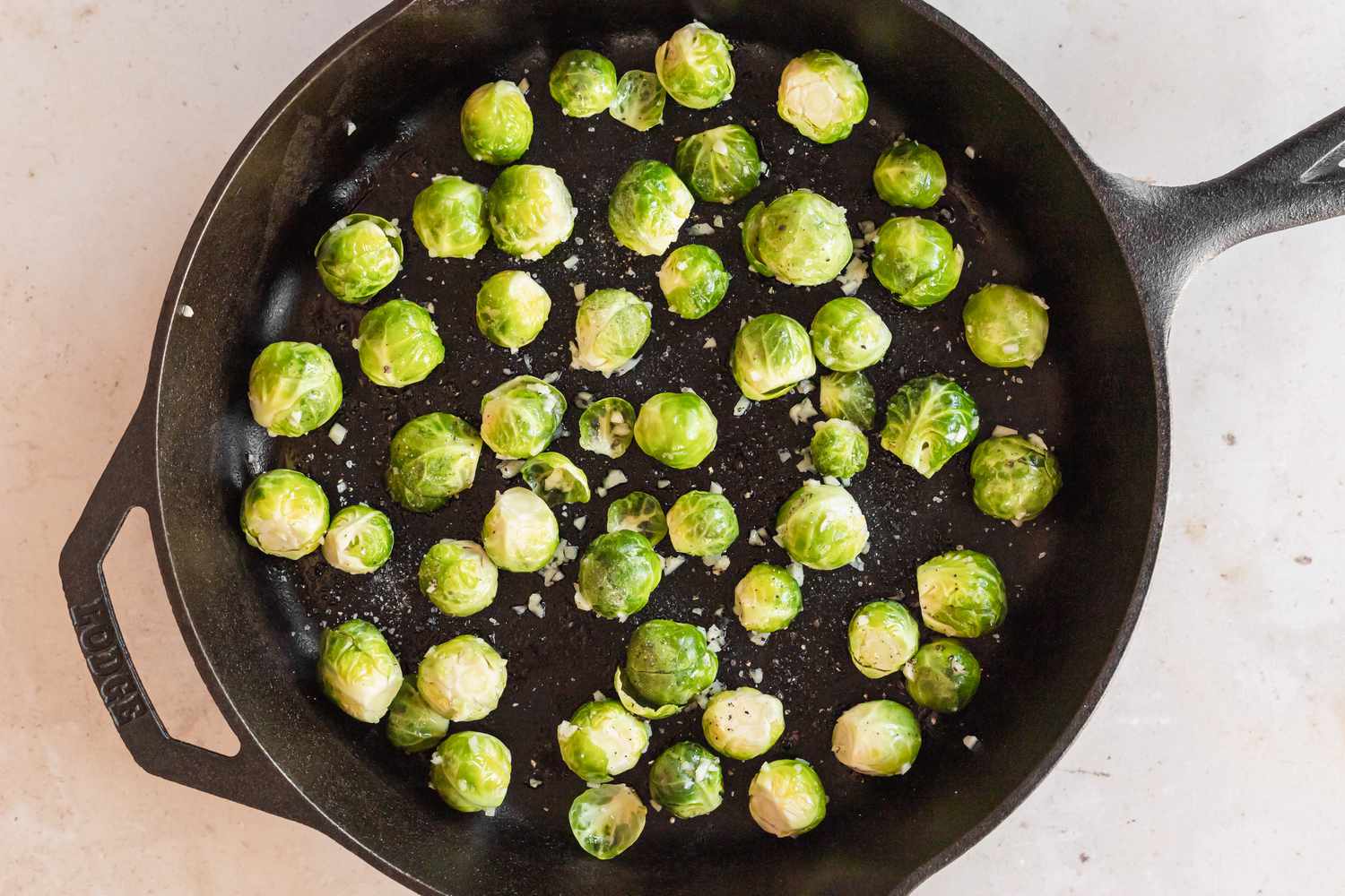 Overhead view of a cast iron skillet to show how to roast brussel sprouts.