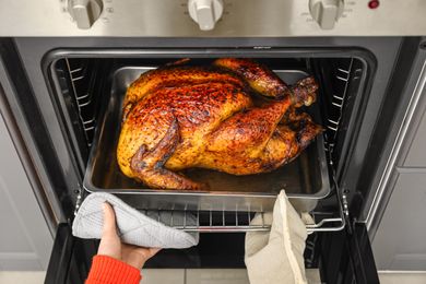 Person removing cooked turkey from an oven