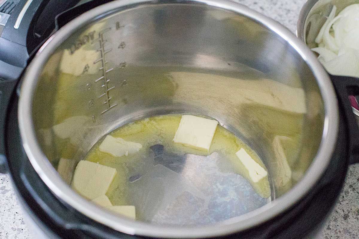 Butter melting in the bottom of an instant pot bowl for pressure cooker French Onion soup.