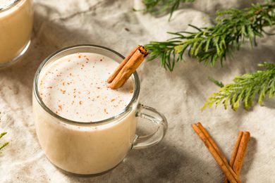 A cup of eggnog with a cinnamon stick