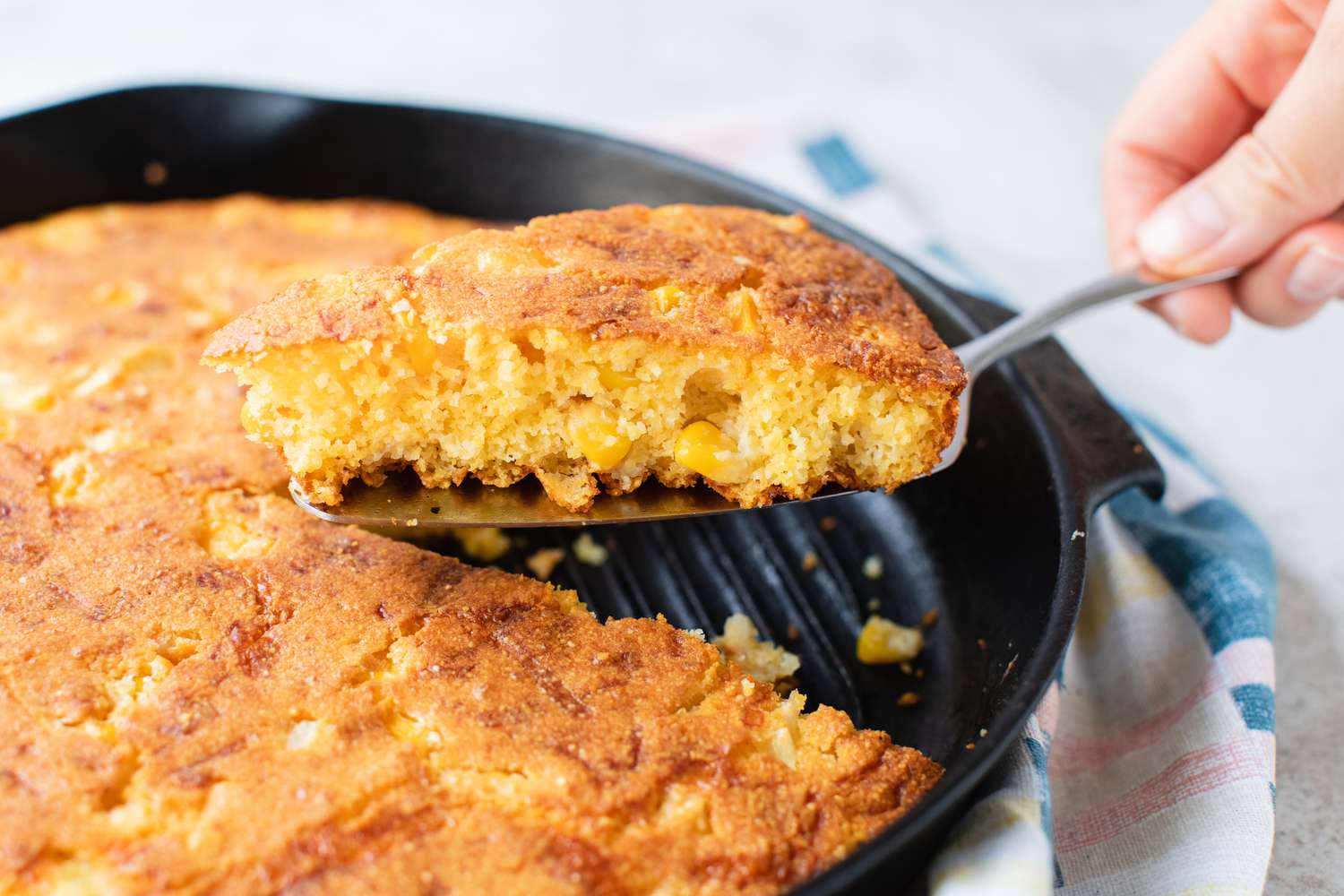 A Serving of Cheesy Skillet Cornbread Lifted from Skillet of More Cornbread