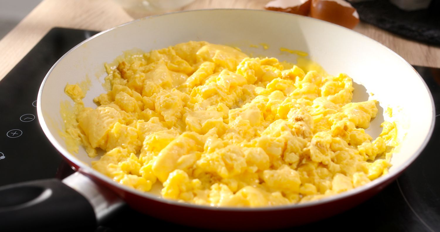 scrambled eggs in a frying pan on a cooktop