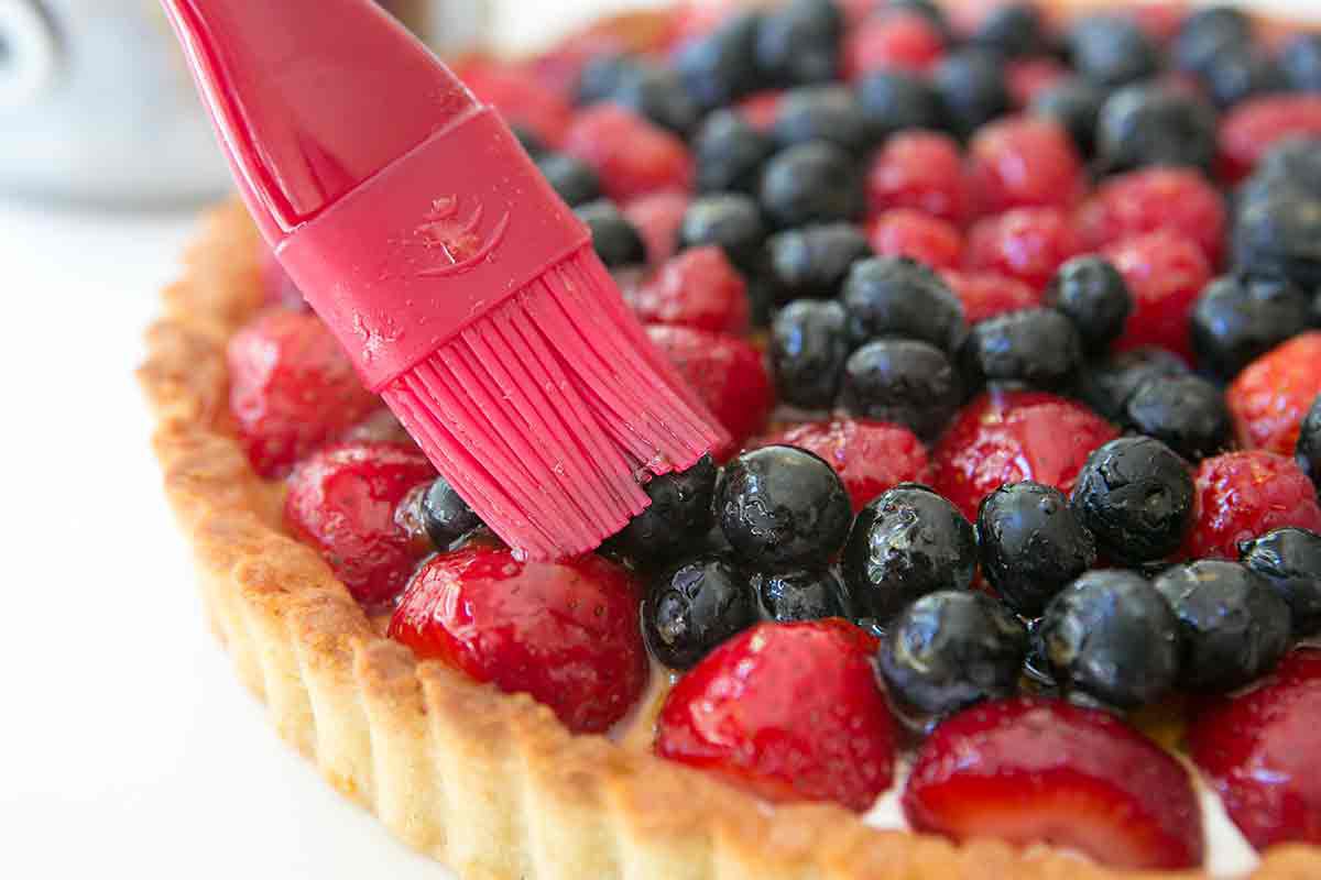 brushing glaze on a fresh berry tart