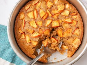 Apple spoon cake in a round baking dish with a portion served using a spoon
