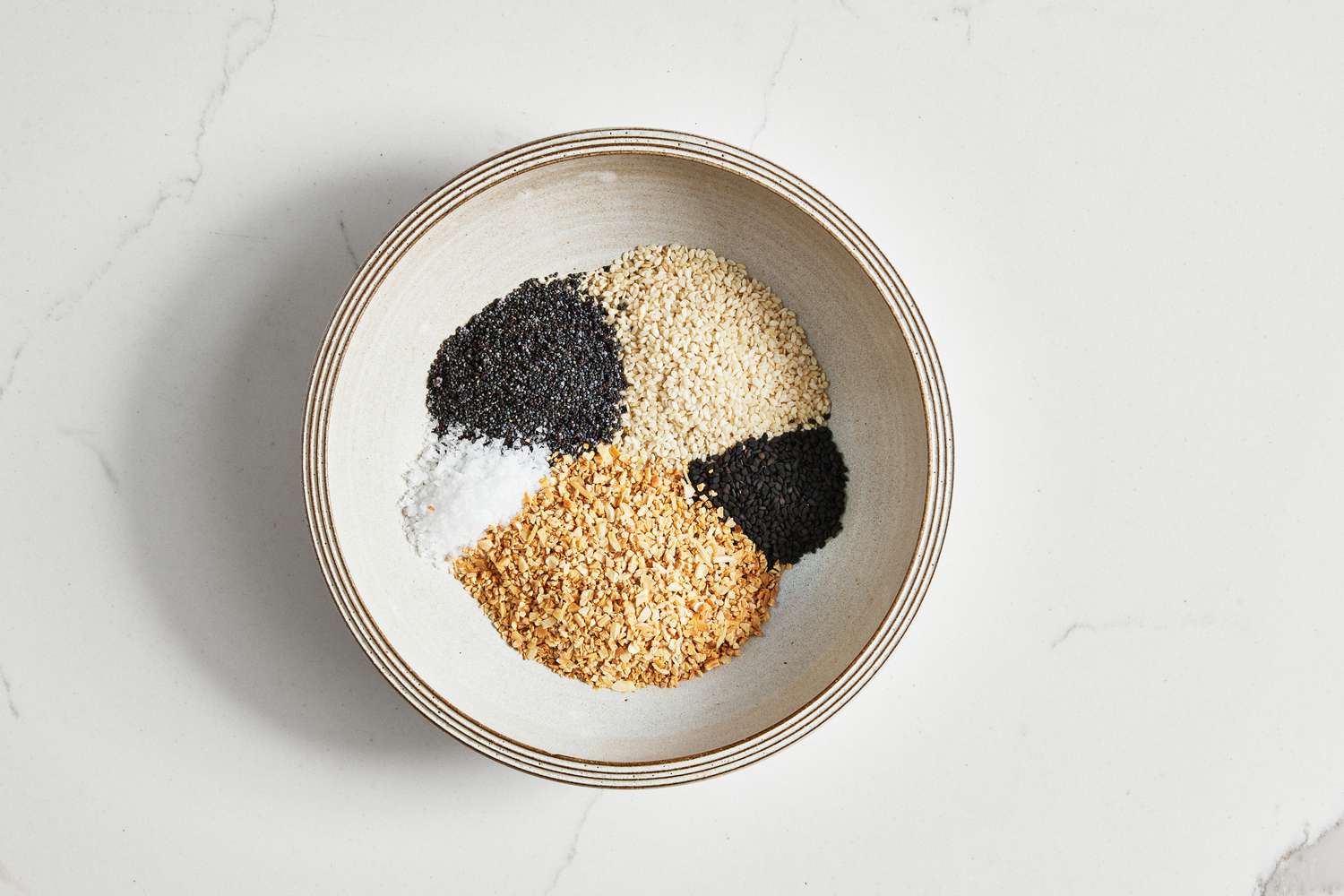 Bowl With Everything Bagel Seasoning Ingredients in Separate Piles 