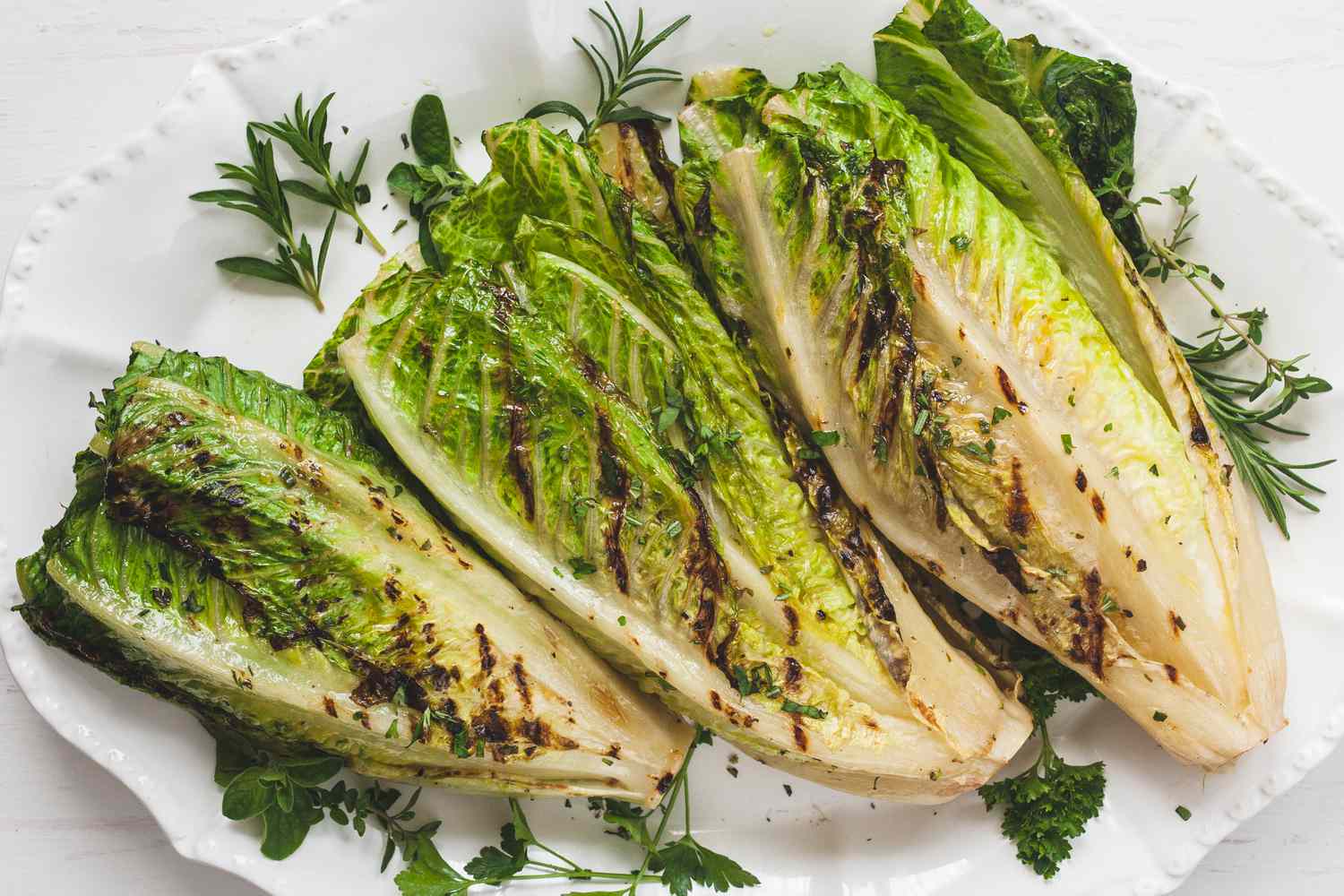 Three grilled romaine hearts on a platter.