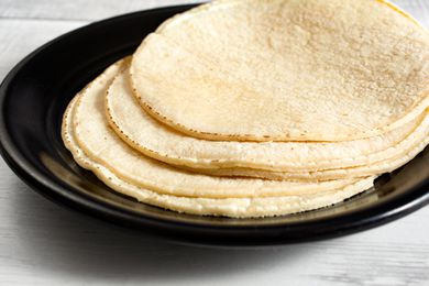 Side shot of a black plate plate with fresh corn tortillas