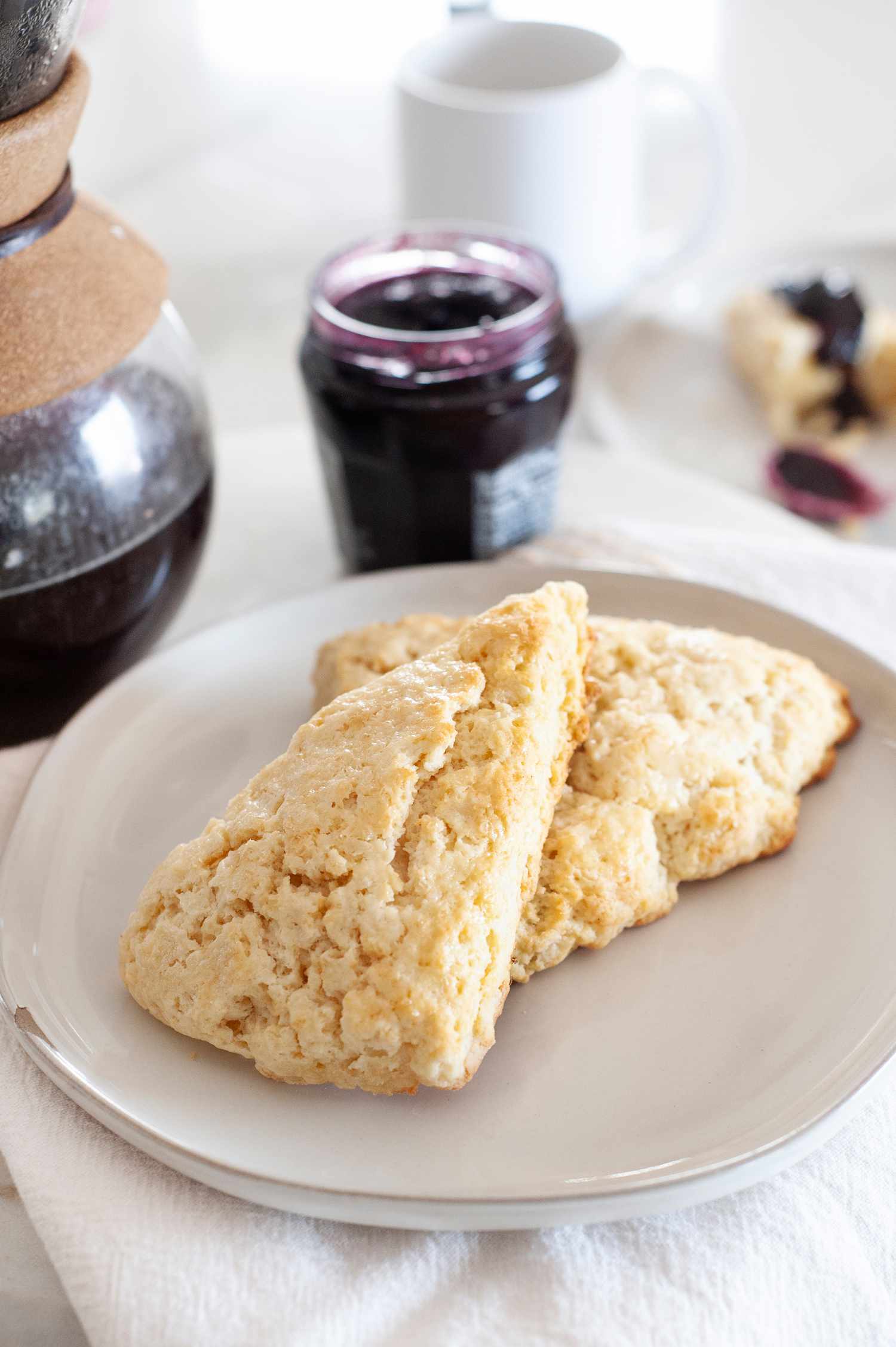 American-Style Scones on a plate with jam and coffee set behind the plate.
