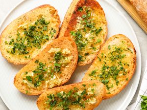 Slices of garlic bread garnished with herbs arranged on a plate