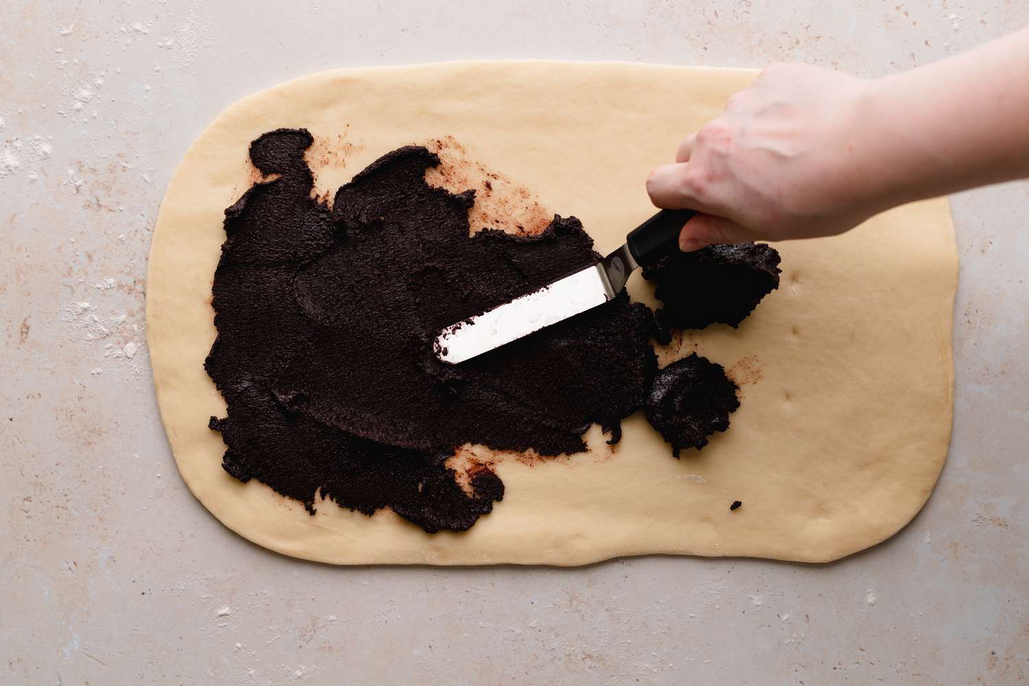 Dough for semi-sweet chocolate babka being spread with chocolate.