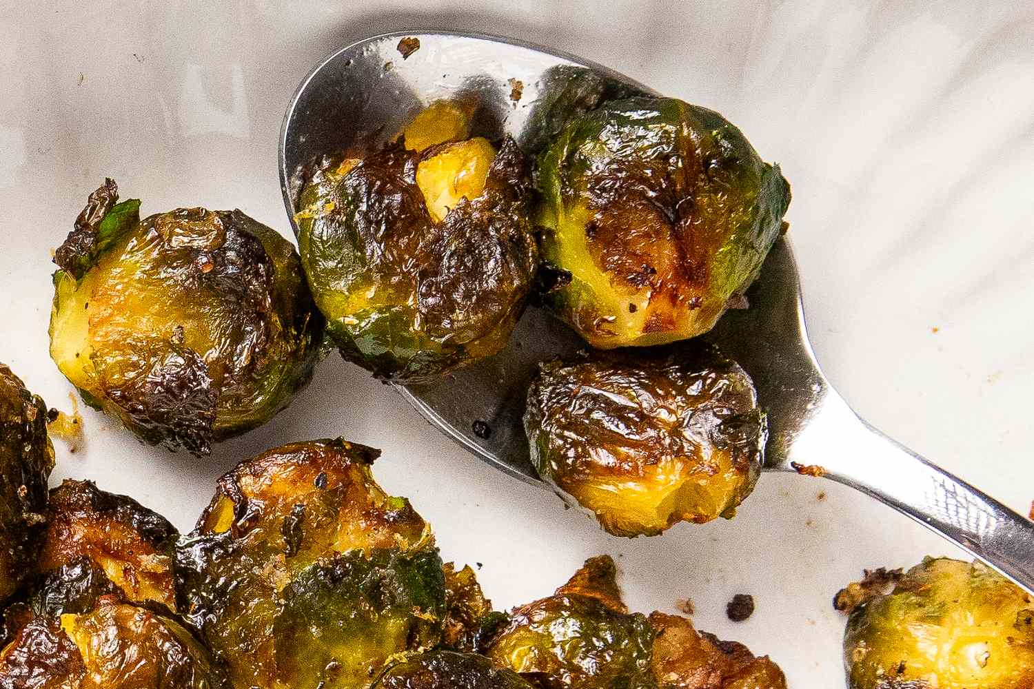 Cooked smashed Brussels sprouts on a serving spoon and dish