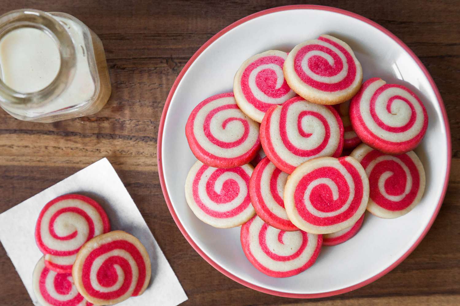 Pile of Holiday Pinwheel Cookies on a Plate and Next to It, a Napkin with More and a Bottle of Milk