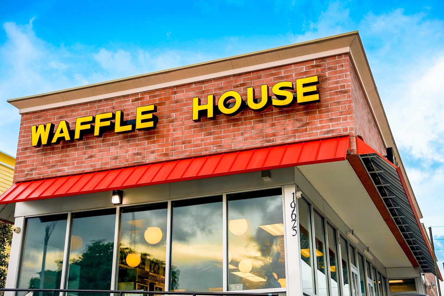 The exterior of a Waffle House restaurant building showing the sign with the name and large windows