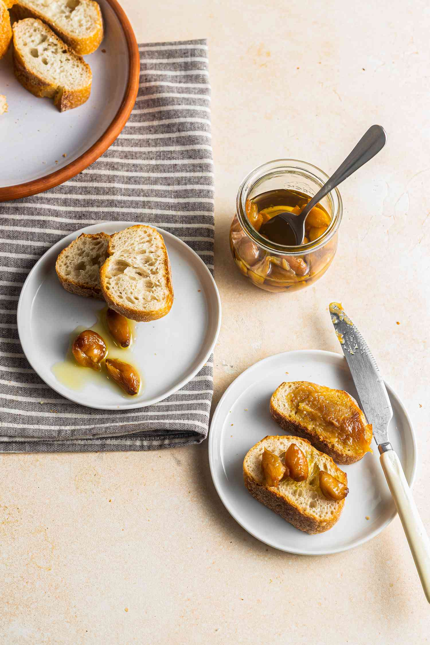Two Plates of Garlic Confit on Toast with More in a Jar