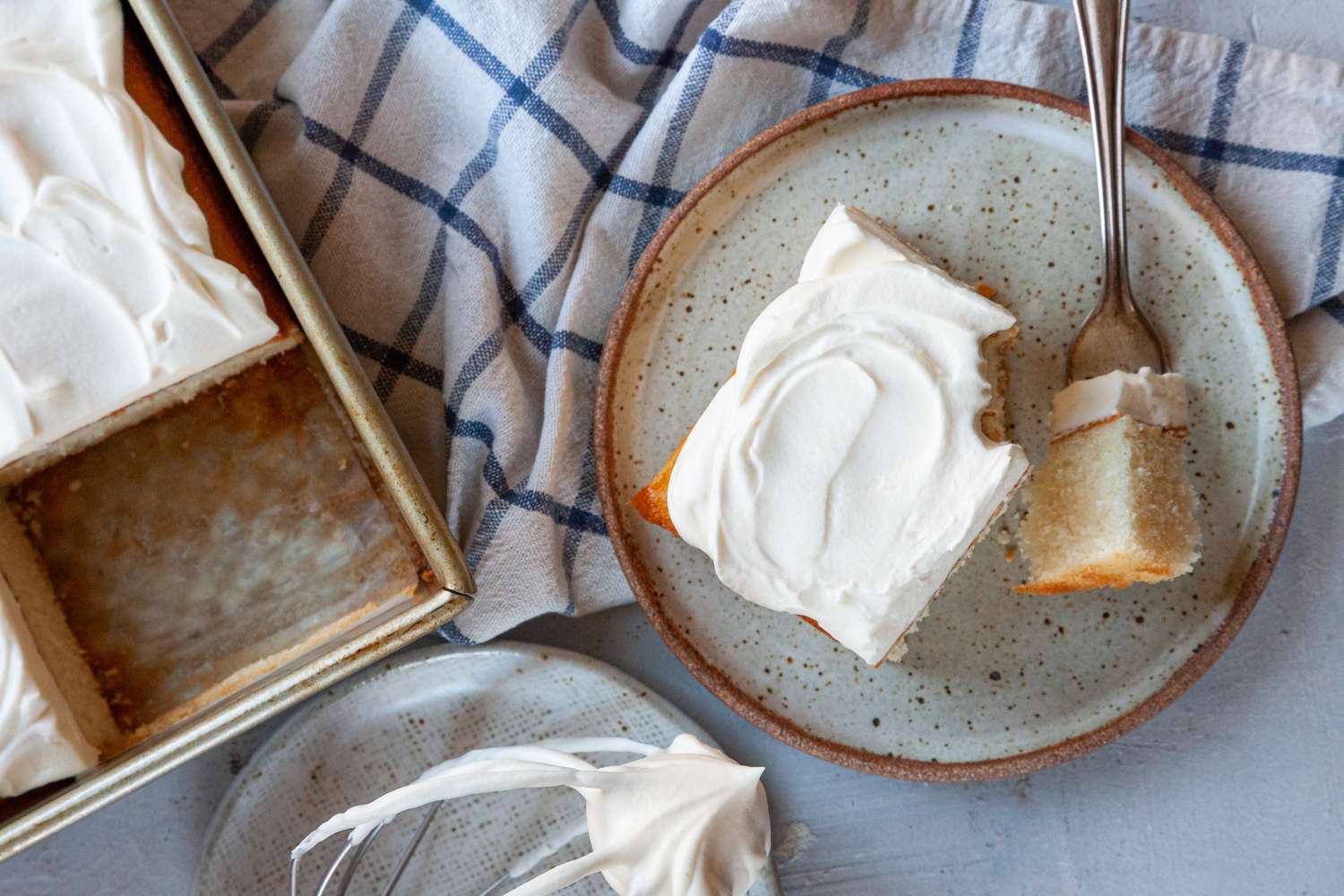 Homemade white cake on a plate with the remaining cake to the left.