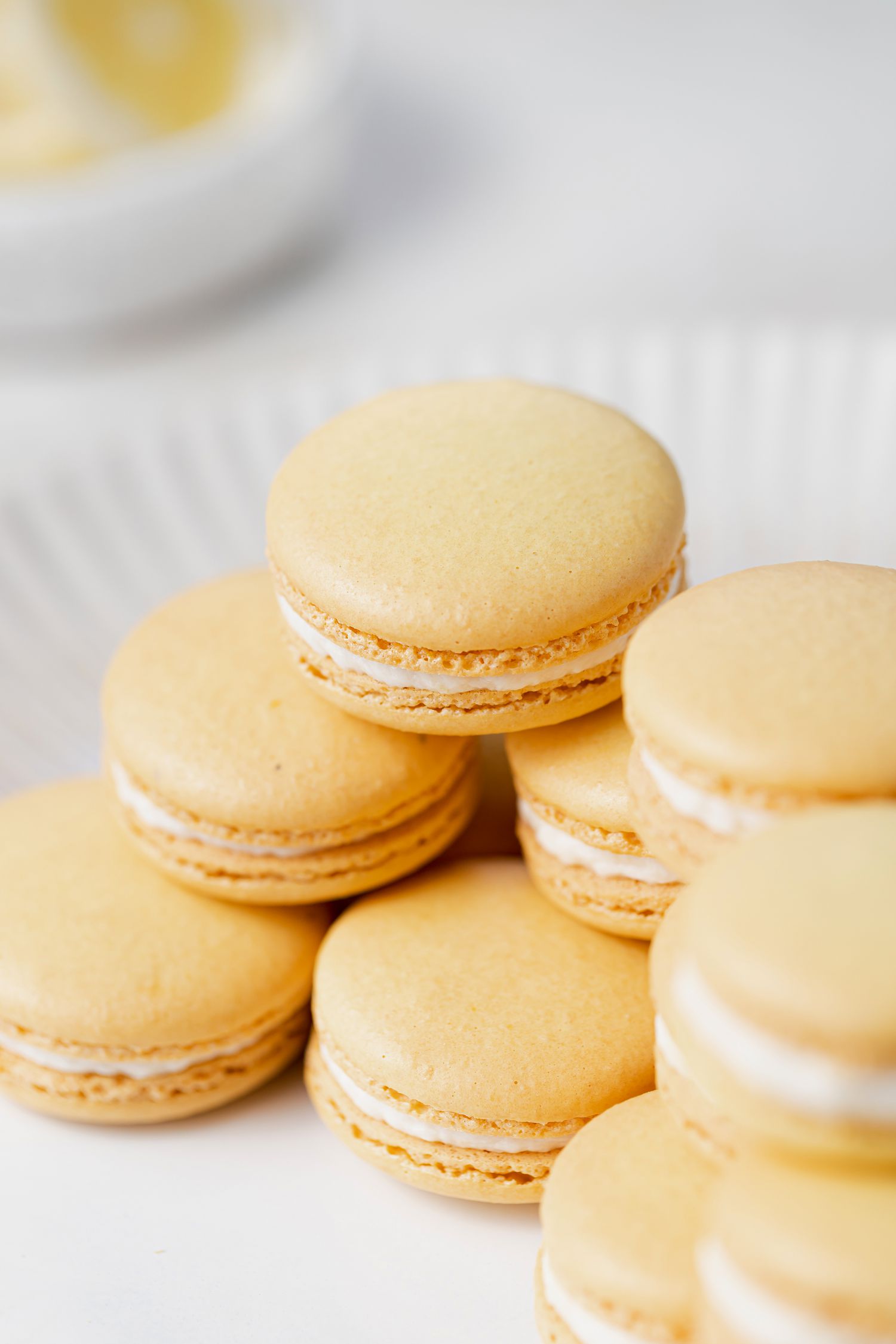 Lemon buttercream macarons set on top of each other on a plate.