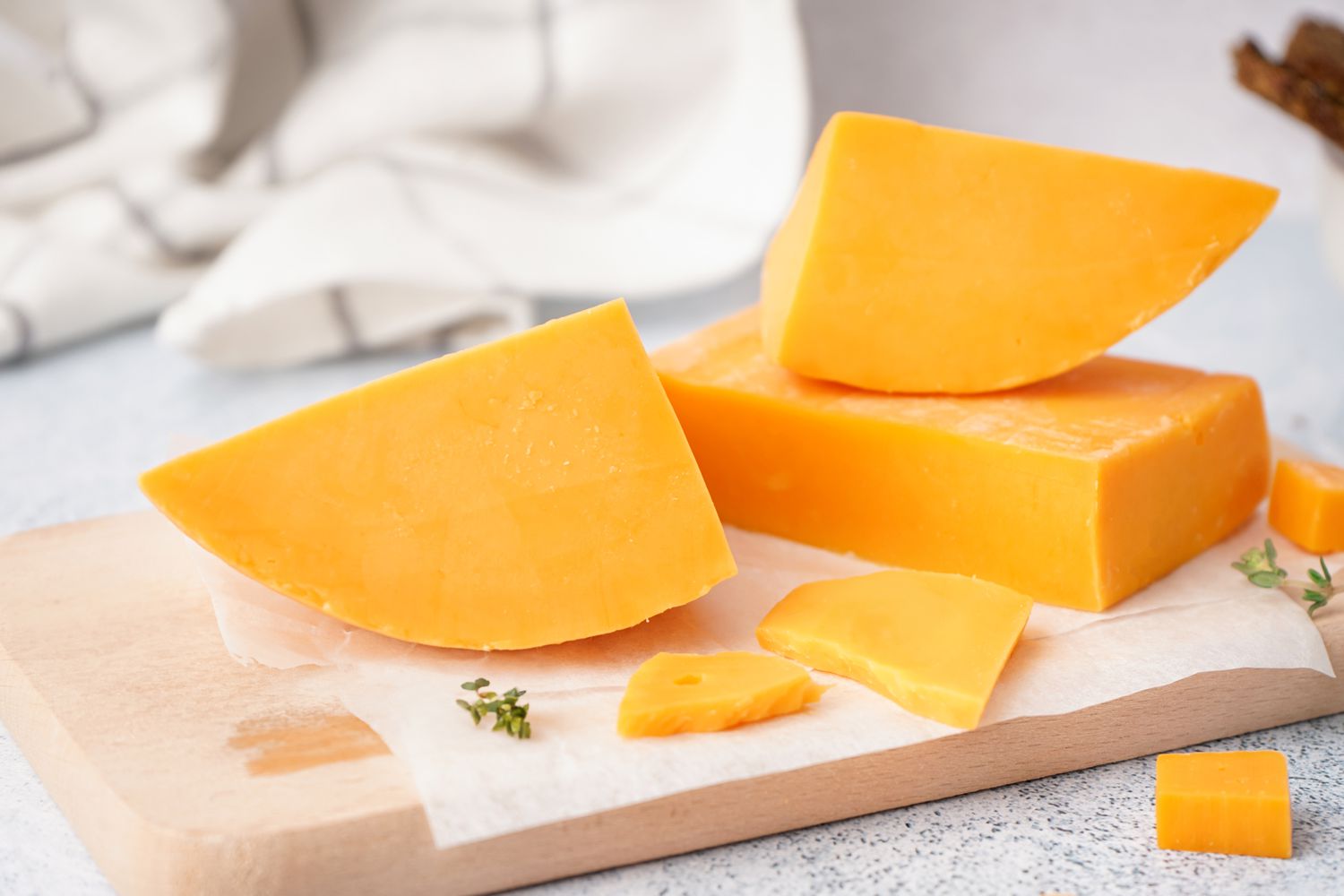 Pieces of yellow cheddar on a cutting board