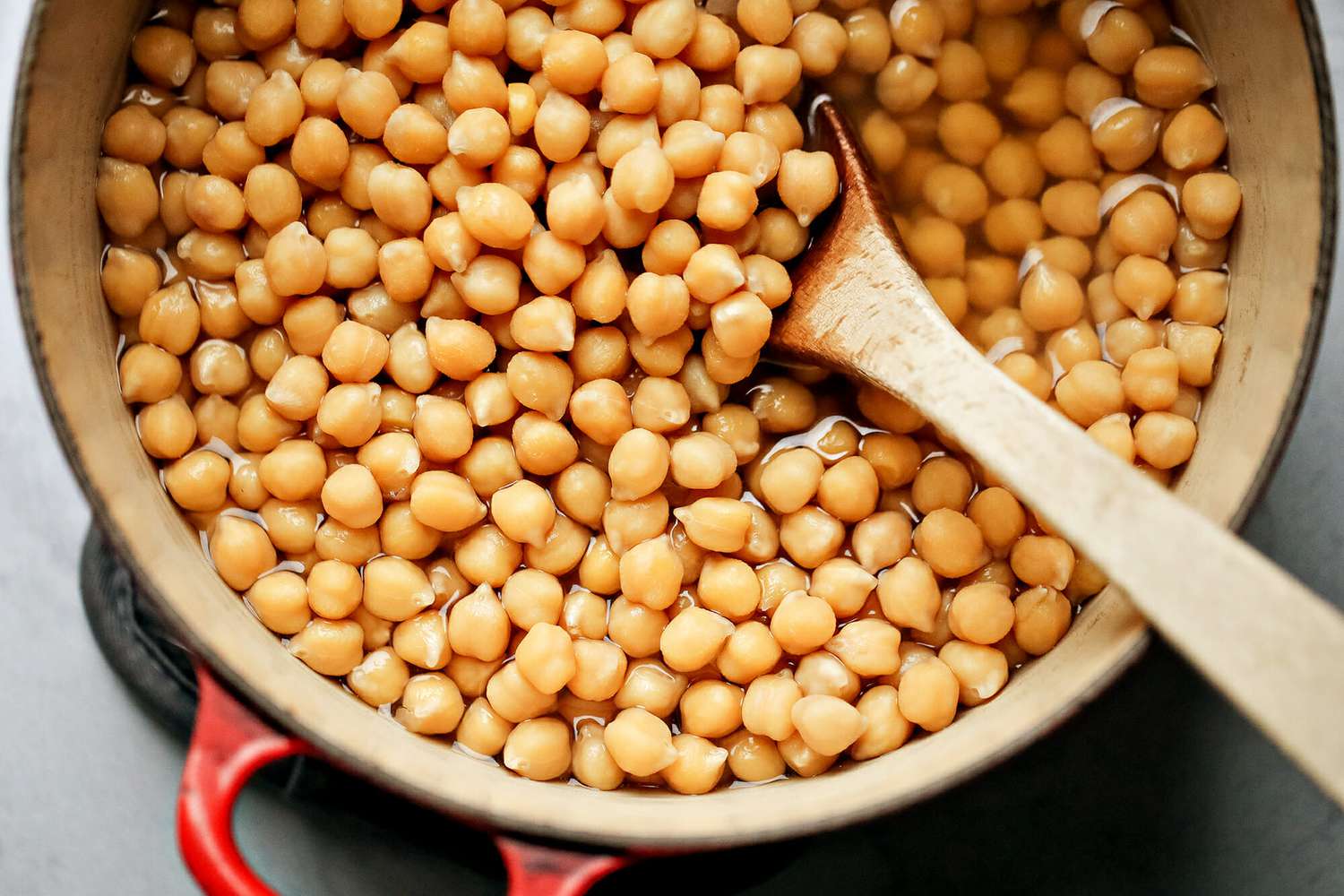 Cooked chickpeas in a pot with a wooden spoon