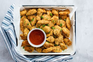 A tray of baked breaded chicken breast served with ketchup.